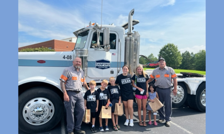 Two SCI Employees with group of children in front of truck