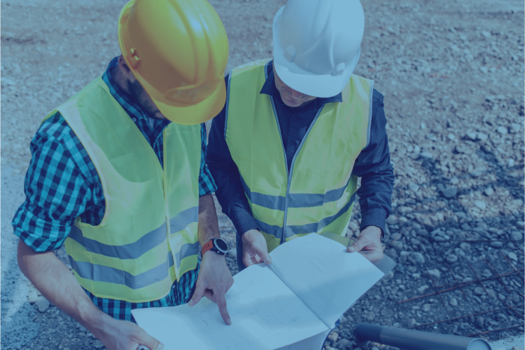 Two construction workers looking at plans in blue hue