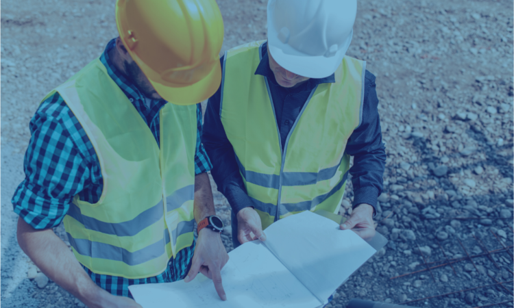 Two construction workers looking at plans in blue hue